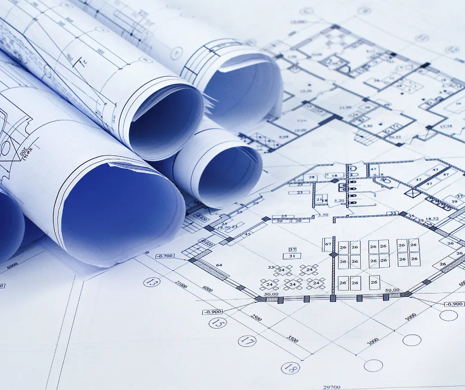 A draughtsman working on technical drawings at a desk.