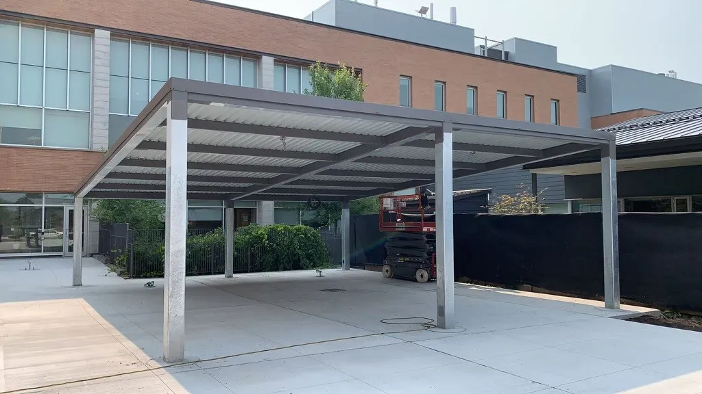 A fabricated steel canopy over a walkway outside a commercial building.